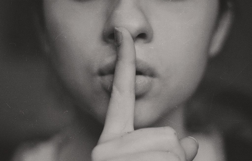 A black and white image of a woman with her finger to her lips.
