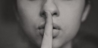 A black and white image of a woman with her finger to her lips.