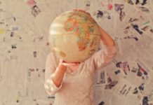 A woman holding a globe against a background of newspapers.