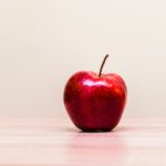 A red apple on an empty desk.