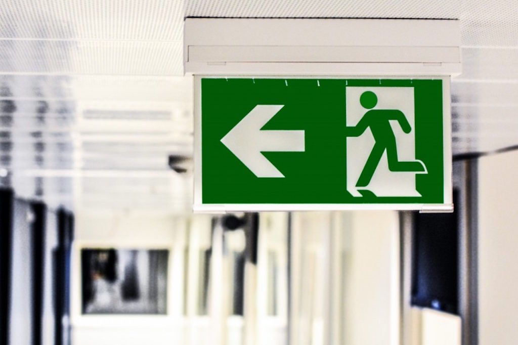 green and white exit sign with corridor in background