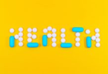 Pills arranged to spell out 'health' against a bright yellow background.