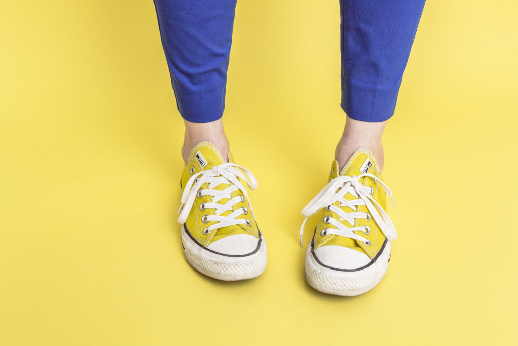 A pair of yellow converses against a yellow background.