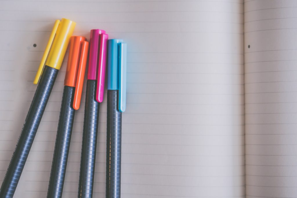 A set of coloured pens on a notebook.