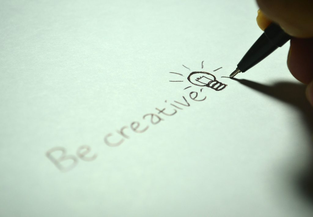 A pen writing "be creative' on paper.
