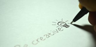 A pen writing "be creative' on paper.