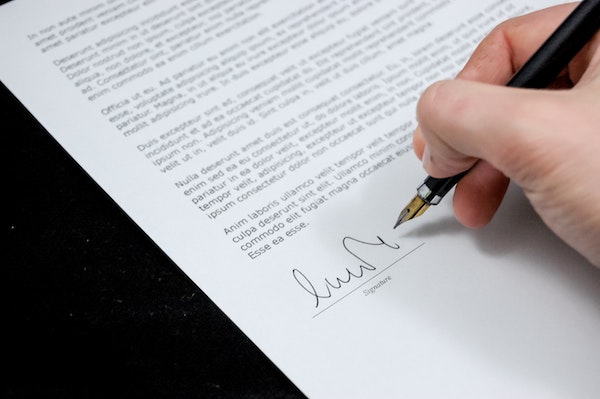 A hand writing a signature on a letter