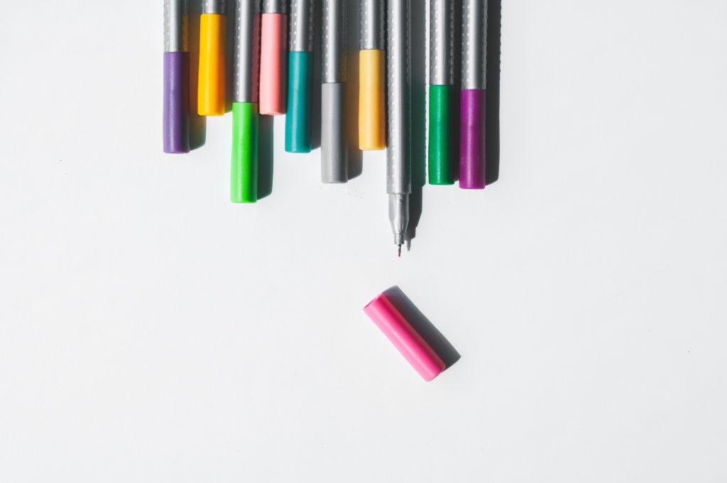 A row of coloured pens against a white background.