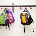 A row of back packs hung up in a school corridor.